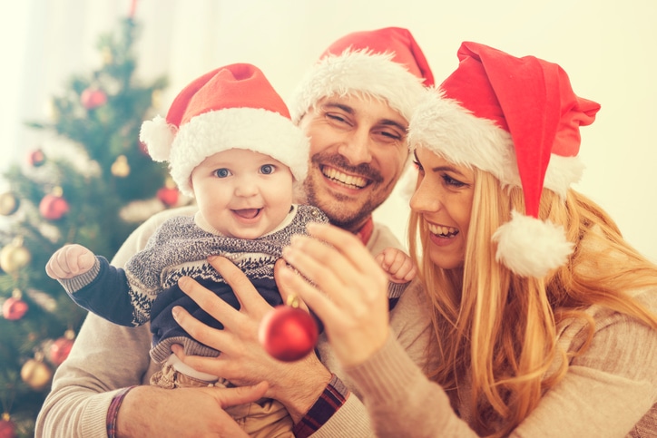 Happy family in the room with the Christmas tree.The family is enjoying in the holidays.They are celebrating their first Christmas together.